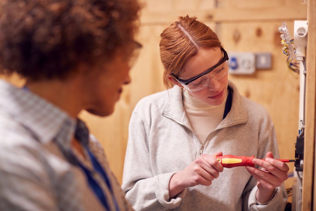 A tutor with a trainee electrician in a college workshop